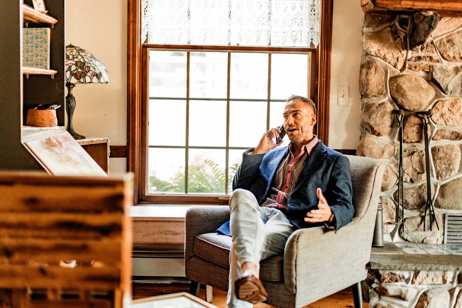 David sitting in an armchair by a window, mid-phone-call.